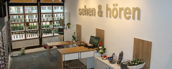 Modernes Optiker- und Akustiker-Geschäft mit Brillen, Dekoration und Empfangstheke.